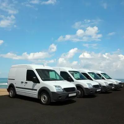 row of white short-wheel base transit connect vans parked by the sea side